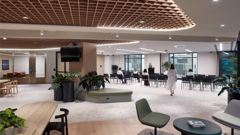 Abacus office workplace hub featuring a premium multifunctional collaboration space with flexible event seating, integrated presentation technology, biophilic planting, timber feature ceilings, and contemporary breakout areas designed to support meetings, training sessions, workplace events, and employee collaboration.