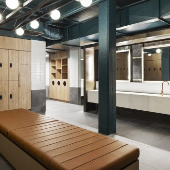 Yarra Falls, Melbourne, featuring premium end-of-trip facilities with timber-finished digital lockers, a contemporary grooming and vanity area, illuminated mirrors, leather bench seating, industrial heritage detailing, and wellness-focused amenities designed to support active commuting, employee wellbeing, and an elevated workplace experience.
