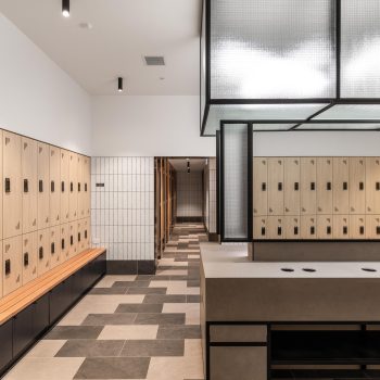 Industry Lanes, Melbourne, featuring premium end-of-trip facilities with secure digital lockers, integrated timber bench seating, textured tiled finishes, contemporary vanity and preparation stations, and industrial-inspired detailing that supports active commuting, employee wellbeing, and a high-quality workplace experience within a heritage-led commercial precinct.